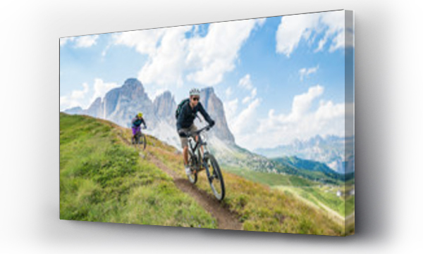 Wizualizacja Obrazu : #109773284 A man and a woman on  mountain bikes racing along trail in the Dolomites,  Val Gardena, Italy