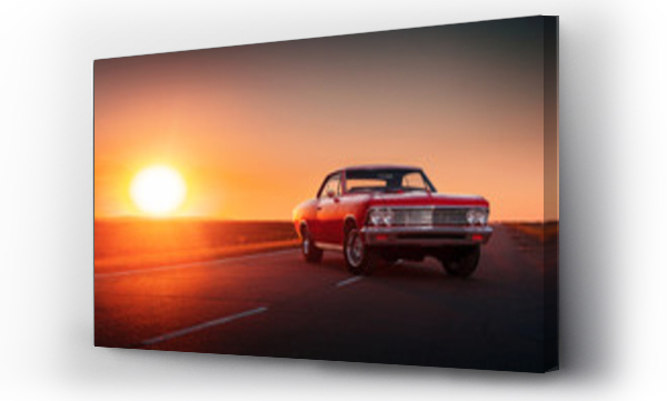 Retro czerwony samochód stojący na asfaltowej drodze przy zachodzie słońca
