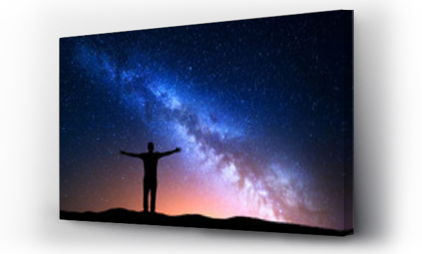 Nocny krajobraz z Milky Way. Sylwetka stojącego młodego człowieka z podniesionymi rękami na górze. Piękny wszechświat. Tło podróży z niebieskim nocnym rozgwieżdżonym niebie