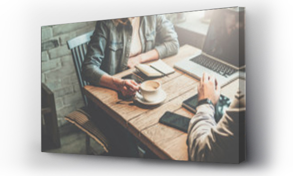 Praca zespołowa. Biznesmen i bizneswoman siedzący przy stole w kawiarni i omawiają biznesplan. Na stole jest laptop, tablet, smartfon, notatnik, filiżanka kawy.Business spotkanie partnerów w kawiarni.