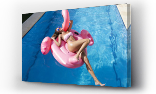 Beztroska młoda kobieta na różowym flamingu w basenie