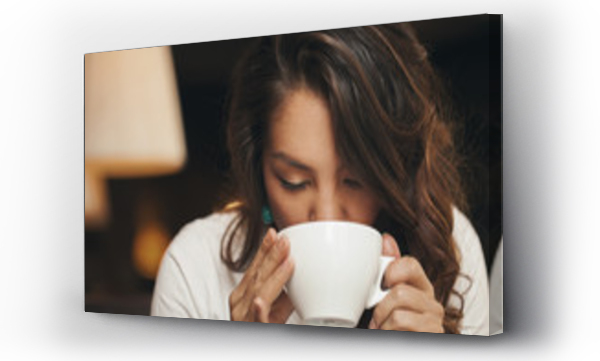 Ładna młoda kobieta pijąca kawę siedząc w kawiarni