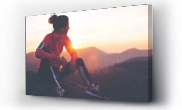 Wysportowana kobieta odpoczywająca po ciężkim treningu w górach przy zachodzie słońca. Sportowe obcisłe ubrania.