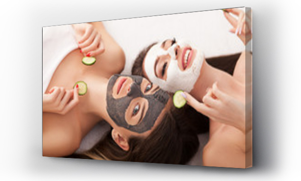 Wizualizacja Obrazu : #181421572 Home spa. Two women holding pieces of cucumber on their faces lying the bed.