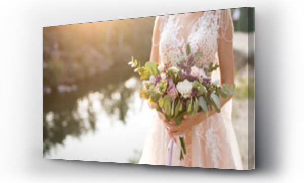 Wizualizacja Obrazu : #192609030 Panna młoda w beżowej sukni ślubnej trzyma bujny bukiet ślubny z liliowych róż i dużo zieleni. Stylowy bukiet ślubny na tle zachodzącego słońca
