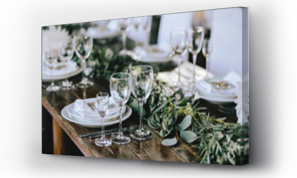 Wizualizacja Obrazu : #193953734 Udekorowany elegancki drewniany stół weselny w stylu rustykalnym z eukaliptusem i kwiatami, porcelanowymi talerzami, kieliszkami, serwetkami i sztućcami.