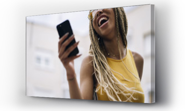 Afro-włosa latynoska kobieta pozująca z telefonem komórkowym.