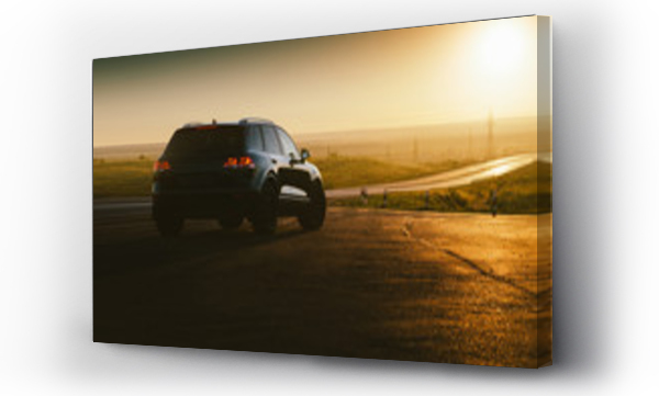 Wizualizacja Obrazu : #213989548 Czarny samochód jest zaparkowany na wiejskiej asfaltowej drodze w pobliżu autostrady przy złotym zachodzie słońca