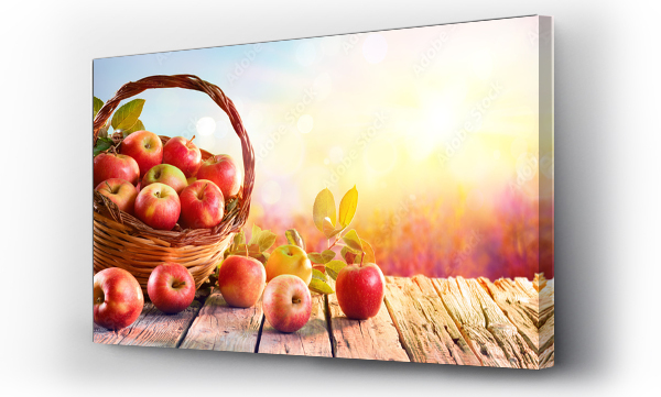 Czerwone jabłka w koszu na starzejącym się stole przy zachodzie słońca