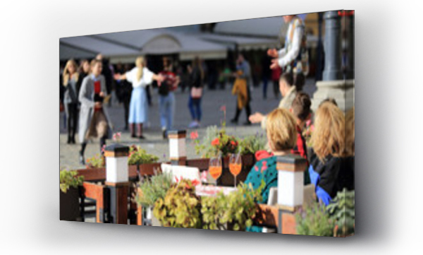 Kobiety pij? pomara?czowe napoje w restauracji, ludzie ta?cz? na rynku miasta.