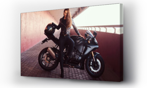 Wizualizacja Obrazu : #230519452 A seductive biker girl leaning on her superbike on a sidewalk inside the bridge on a sunny day.