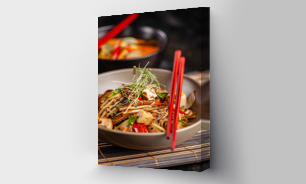Wizualizacja Obrazu : #245985853 The concept of Japanese cuisine. Chinese noodles with chicken, grilled vegetables, and tofu in unagi sauce. Serving Asian dishes in the restaurant in a plate on a bamboo mat. Top view, copy space