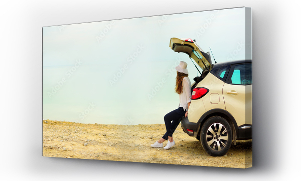 Wizualizacja Obrazu : #259178343 Widok młodej kobiety podróżniczki patrzącej na zachód słońca nad morzem, siedzącej na samochodzie typu hatchback z miejscem na kopię. Banner