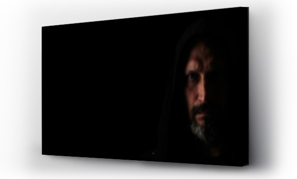 Wizualizacja Obrazu : #269333650 Brutal man with a gray beard in the hood with sharp shadows on a black background. Copy space.