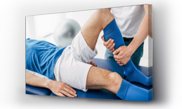 Wizualizacja Obrazu : #272736009 Cropped view of Physiotherapist massaging leg of football player in hospital