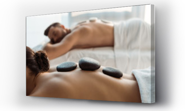 selektywna ostrość kobiety wykonującej masaż kamieniami w pobliżu mężczyzny w centrum spa