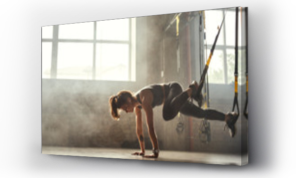 Wizualizacja Obrazu : #279281499 Trening TRX. Młoda wysportowana kobieta w sportowym ubraniu trenująca nogi z pasami TRX fitness na siłowni.