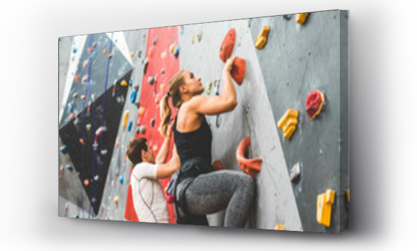 Para sportowców wspinających się po stromej skale, wspinaczka na sztucznej ścianie w pomieszczeniach zamkniętych. Sporty ekstremalne i koncepcja boulderingu