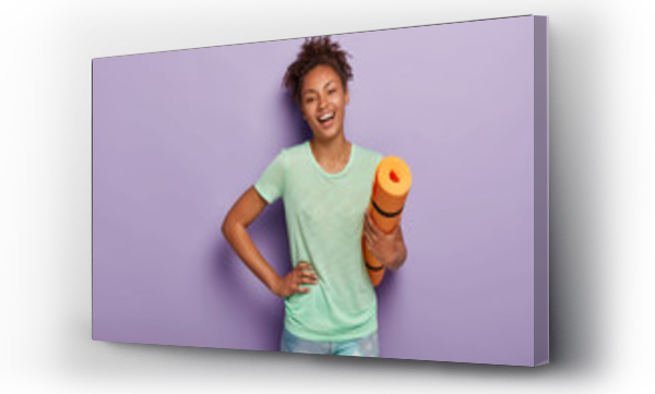 Wizualizacja Obrazu : #283242362 Fit positive Afro woman does fitness exercises and workout at home, holds orange karemat, keeps one hand on waist, wears casual t shirt and leggings, wants to loose weight, be healthy. Time to sport