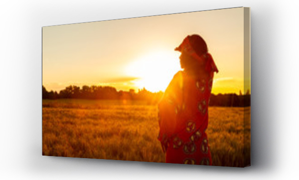 Wizualizacja Obrazu : #293141357 African woman in traditional clothes standing in a field of crops at sunset or sunrise