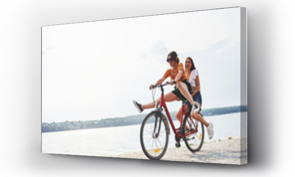 Wizualizacja Obrazu : #302469824 Two female friends on the bike have fun at beach near the lake