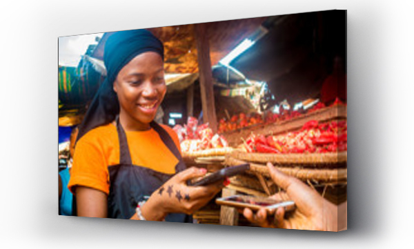 młoda afrykanka sprzedająca pomidory na lokalnym afrykańskim targu otrzymuje zapłatę przelewem z telefonu komórkowego