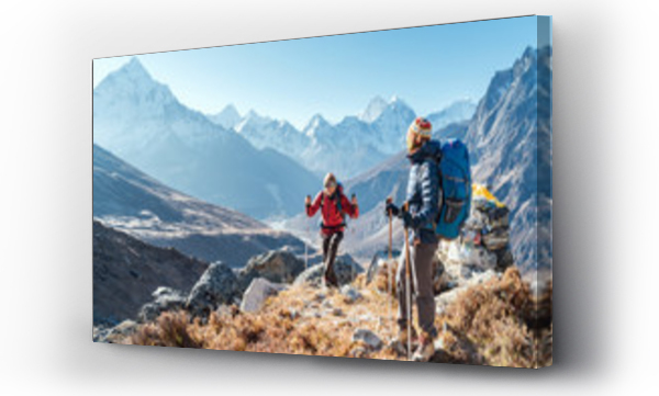 Para podążająca trasą trekkingową Everest Base Camp w pobliżu Dughla 4620m. Plecakowcy niosący plecaki i używający kijków trekkingowych, podziwiający widok doliny z Ama Dablam 6812m