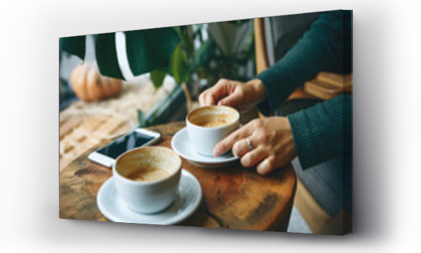 Wizualizacja Obrazu : #313477813 Dziewczyna pije kawę w kawiarni podczas spotkania. Nieopodal, na stoliku leży telefon komórkowy.