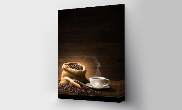 Filiżanka kawy z dymem i ziarnami kawy na starym drewnianym tle