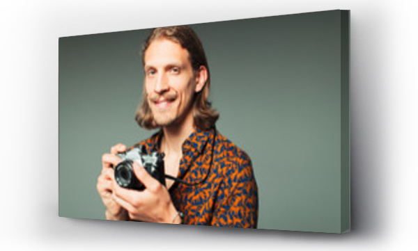 Portret pewny siebie młody mężczyzna z wąsami trzymający aparat fotograficzny retro