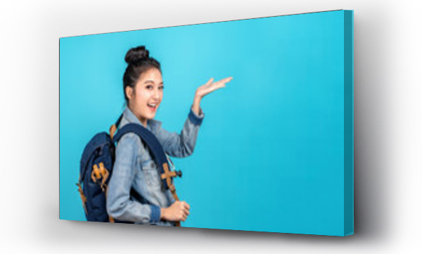 Wizualizacja Obrazu : #328999452 Happy asian kobieta podróży backpacker stojący ręka otwarta do copyspace na niebieskim tle. Cute asia dziewczyna uśmiechnięta noszenie dorywczo dżinsy koszuli i palec wskazujący na bok na promocje prezentów.