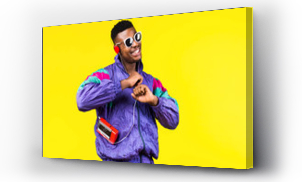 Wizualizacja Obrazu : #334854438 African American young man, in a jacket in the style of the 90s, with a retro cassette player, hears music, the mood of dancing and fun, yellow and purple colors