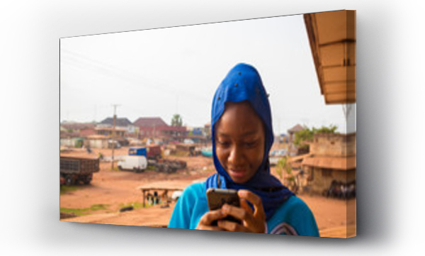 Piękna afrykańska muzułmanka czuje się podekscytowana, gdy obsługuje swój telefon komórkowy.