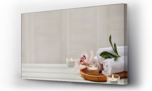 Wizualizacja Obrazu : #336195091 Spa composition with aromatic candles, orchid flower and towel on white wooden table. Beauty spa treatment. copy space