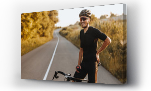 Wizualizacja Obrazu : #341677811 Cheerful bearded man in activewear, black helmet and sport glasses sitting on bike and looking on camera with beautiful nature around. Concept of active and healthy lifestyle.