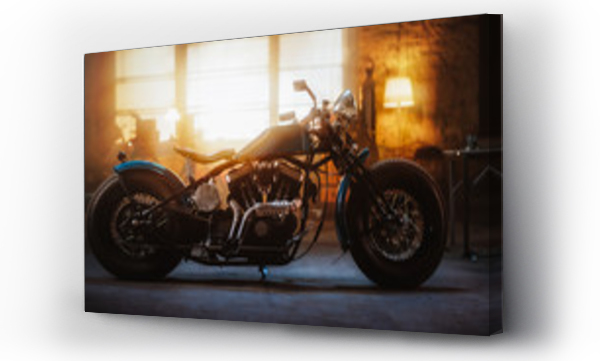 Custom Bobber Motorbike stojący w autentycznym warsztacie twórczym. Motocykl w stylu vintage pod ciepłym światłem lampy w garażu. Widok z profilu.