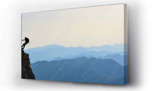 Szalony alpinista wspinający się na skały przy zachodzącym słońcu