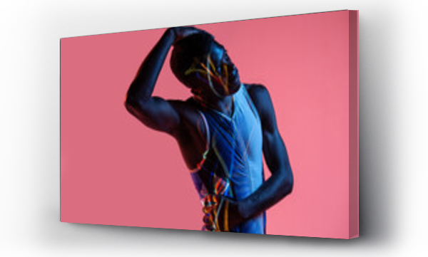 Wizualizacja Obrazu : #380746582 Professional young African American sportsman in active wear performing stretching exercise during training in studio with colorful background and neon lights with eyes closed