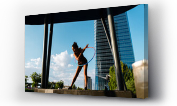 Wizualizacja Obrazu : #397846828 Sporty woman exercising with plastic hoops in modern city against blue sky