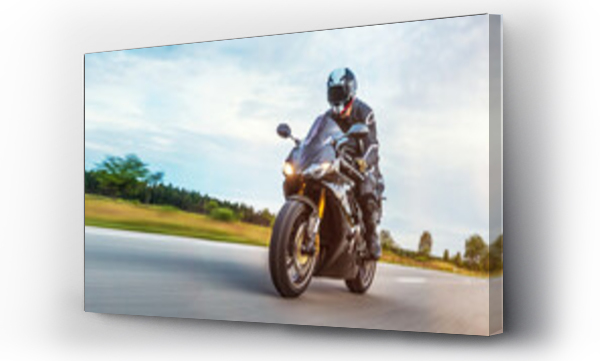 Mężczyzna jadący motocyklem po drodze na tle pochmurnego nieba