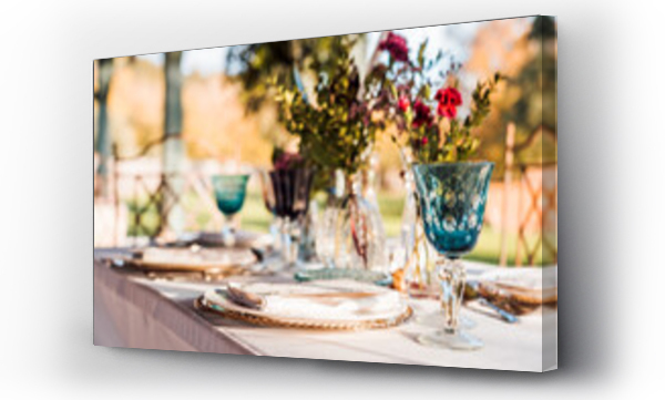 Wizualizacja Obrazu : #419465882 Zbliżenie na podany świąteczny stół z kryształowymi kieliszkami, sztućcami, serwetką na talerzu w pobliżu wiązanki świeżych kwiatów na wesele