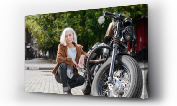 Wizualizacja Obrazu : #440142874 Mature woman crouching by motorcycle on sunny day
