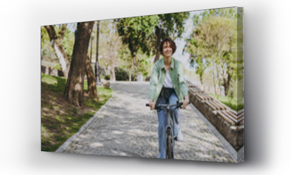 Wizualizacja Obrazu : #440629698 Young fun dreamful happy woman 20s wearing casual green jacket jeans riding bicycle bike on sidewalk in city spring park outdoors, look aside. People active urban healthy lifestyle cycling concept