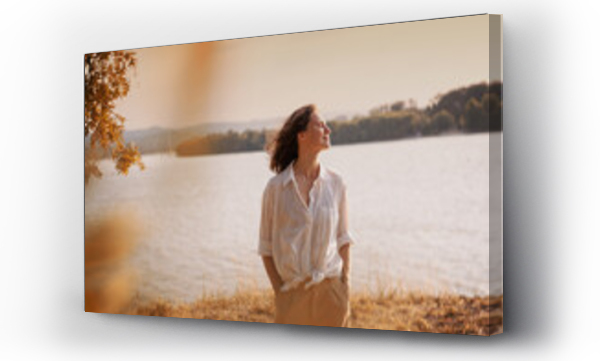 Wizualizacja Obrazu : #452674172 Beautiful young relaxed woman in white blouse enjoying nature breathing fresh air meditating on the river on an autumn day