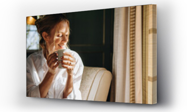 Wizualizacja Obrazu : #456936422 Smiling young woman enjoying a cup of coffee in a hotel