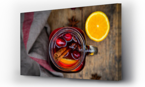 Wizualizacja Obrazu : #462793517 Glass of mulled wine with cranberries, cinnamon sticks, orange and star anise on dark wood, focus on foreground