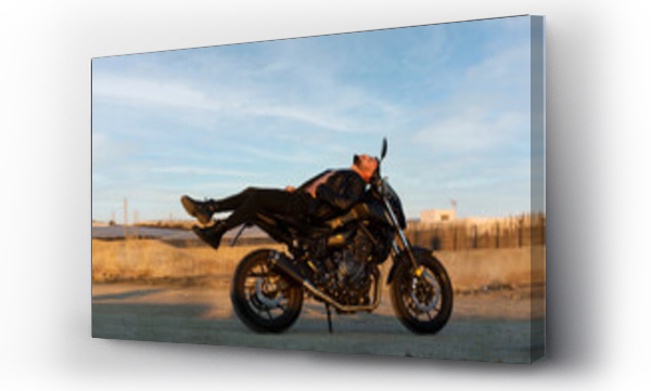 Wizualizacja Obrazu : #462849160 Male biker lying on motorcycle against sky on sunny day