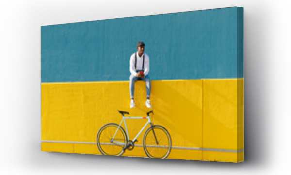 Wizualizacja Obrazu : #483389302 Man with smart phone and bicycle sitting on yellow wall