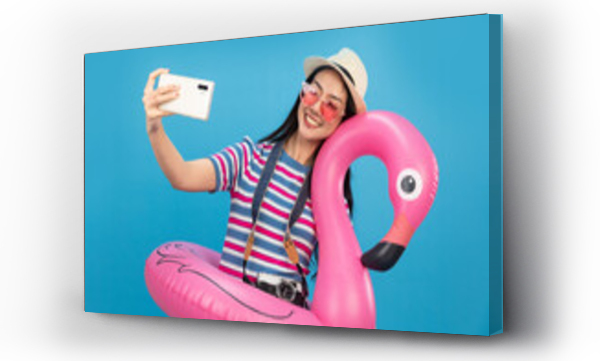 Wizualizacja Obrazu : #486100153 Happy smiling  asian woman holding flamingo rubber ring and enjoying their summer vacation .Young  woman isolated on colour blue background in vacation with travel .