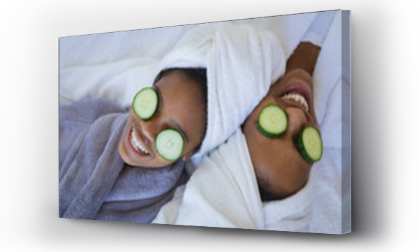 Wizualizacja Obrazu : #498423447 Mother and daughter in bathrobes smiling while relaxing with cucumber slices on eyes at spa